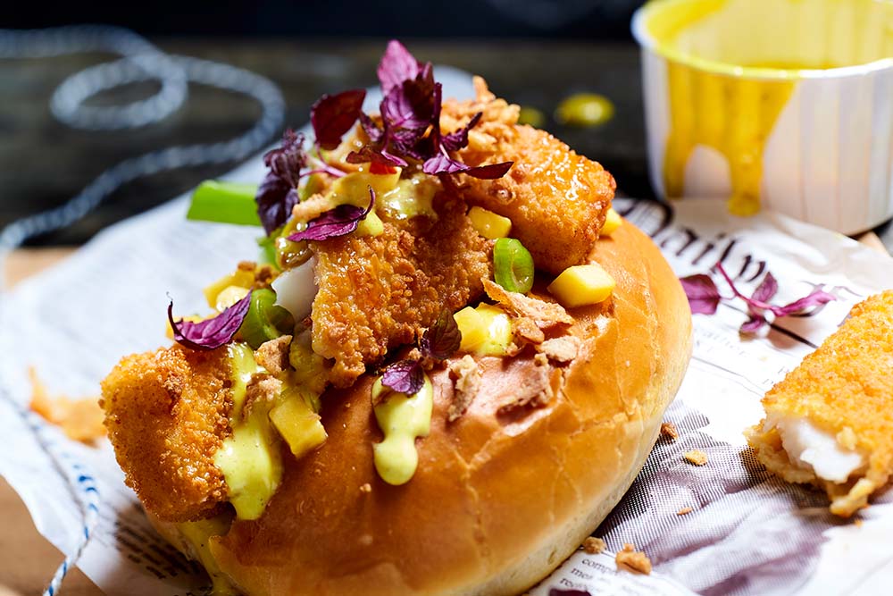 „Fisch“-Hot-Dog mit Mango, Ananas-Mayonnaise und Röstzwiebeln